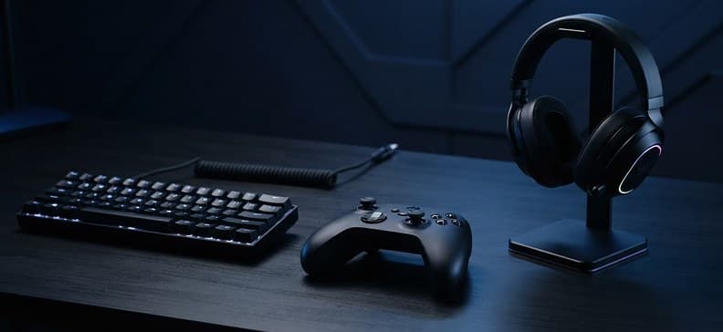 Tastatur, kontroller og headset på en mørk pult